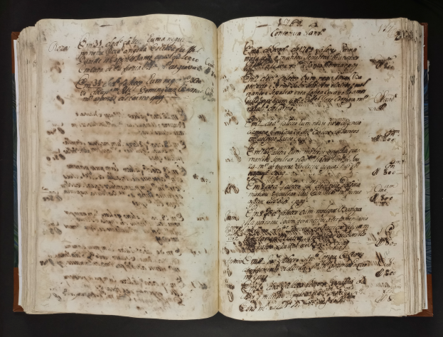 Ein offenes Manuskript aus dem 16. Jahrhundert mit Text auf seinen Seiten vor einem schwarzen Hintergrund.