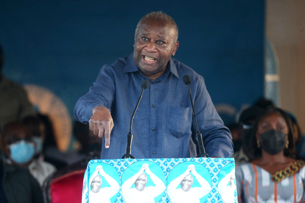 Ein Mann in einem blauen Hemd spricht in zwei Mikrofone an einem Rednerpult, mit einer sitzenden Menge und einer Wand im Hintergrund, wahrscheinlich hält er eine Rede im Zusammenhang mit dem Tod des südafrikanischen Präsidenten.