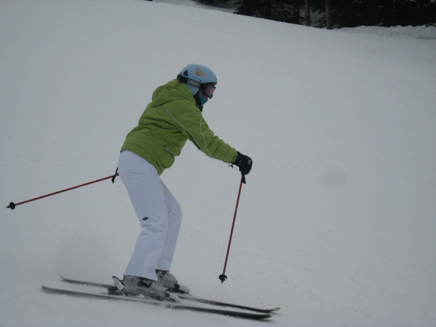 Eine Person, die eine schneebedeckte Piste mit vielen Bäumen hinunterfährt.