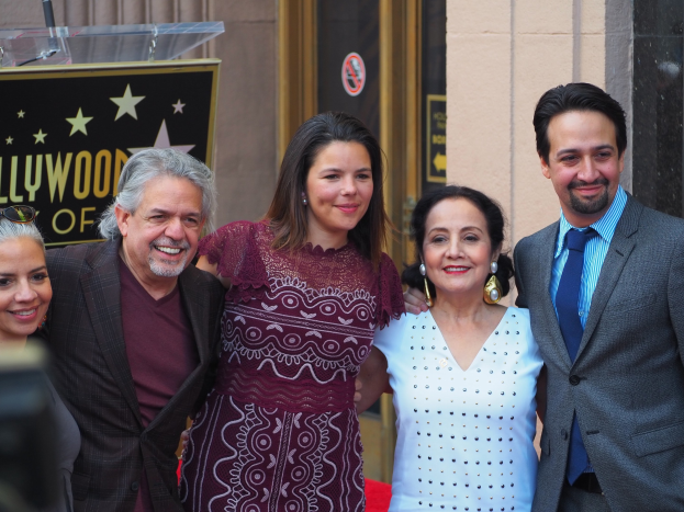 Gruppe von Menschen auf einem roten Teppich bei der Zeremonie des Hollywood Walk of Fame mit einer Tafel, Glaspodest und Wand im Hintergrund.