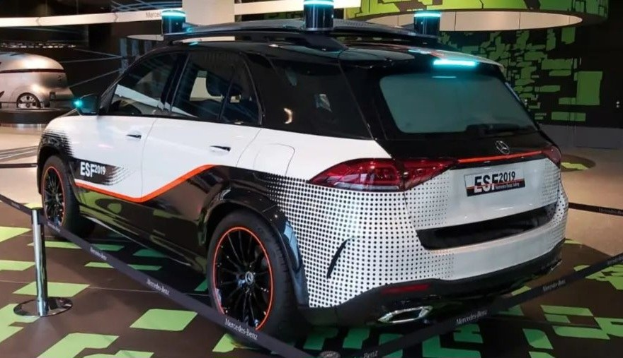 Mercedes-Benz E-Klasse Electric SUV auf der IAA in Frankfurt präsentiert, umgeben von Absperrpollern mit Seilen und Lichtern, mit einem weiteren Fahrzeug und Text an der Wand im Hintergrund.