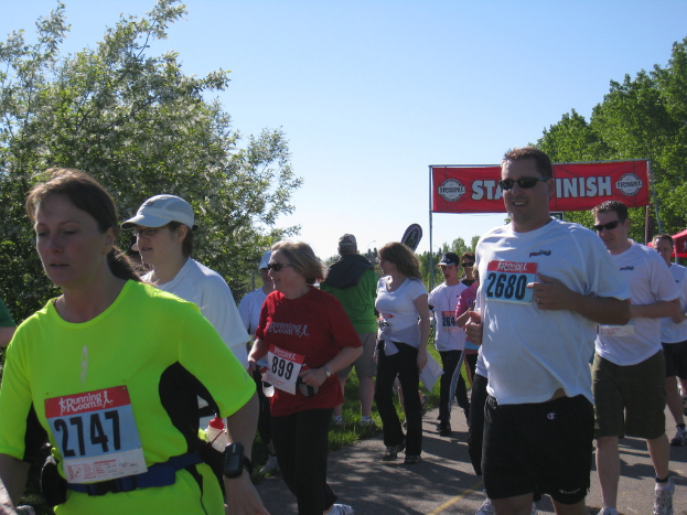 Eine Gruppe von Kindern bei einem Marathonlauf, mit einer roten Fahne und B├Ąumen im Hintergrund.