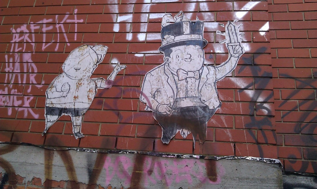 Eine Ziegelwand mit verschiedenen Plakaten und Graffiti.