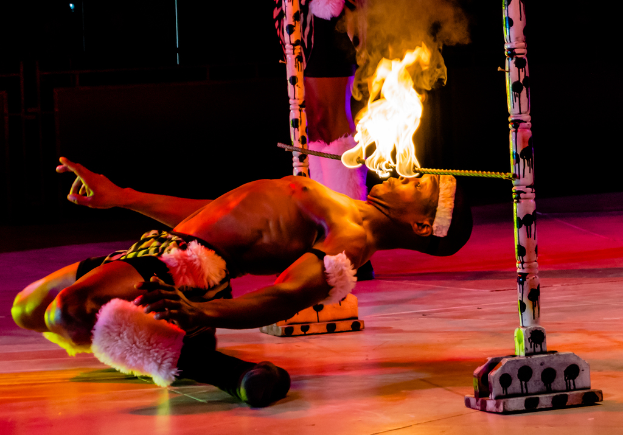 Eine Person schaut auf ein Feuer, das auf einem Stab brennt, der an zwei Polen befestigt ist.