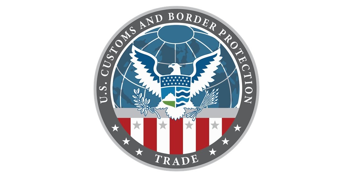 Logo der U.S. Customs and Border Protection Trade mit einem blauen Kreis mit einem weißen Stern, einer weißen Taube mit ausgebreiteten Flügeln und dem Text "U.S." darüber, alles auf einem weißen Rand.