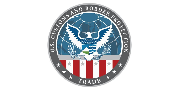 Logo der U.S. Customs and Border Protection Trade mit einem blauen Kreis mit einem weißen Stern, einer weißen Taube mit ausgebreiteten Flügeln und dem Text "U.S." darüber, alles auf einem weißen Rand.