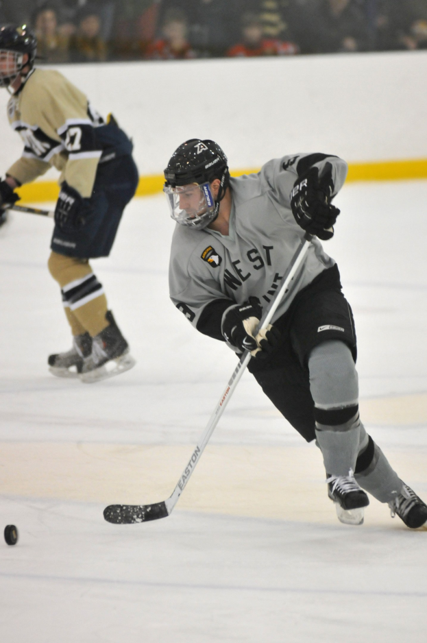 Zwei Männer in Hockey-Ausrüstung, einschließlich Helmen und Schlägern, die auf einem Eisstadion spielen.