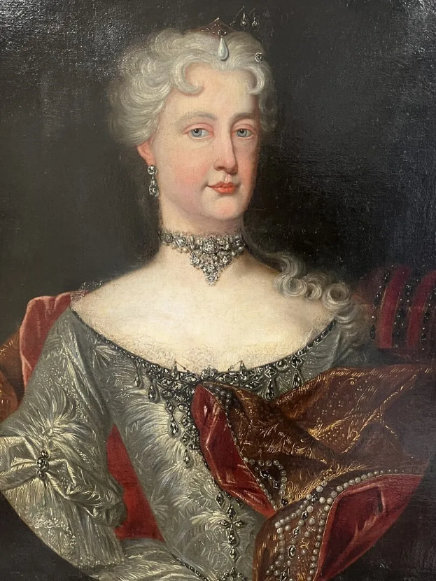 Ein Bild einer Frau in einem roten Kleid, die mutmaßlich Queen Victoria ist, mit dunklem Hintergrund, einem Collier und einer königlich gestylten Frisur, mit feinen Gesichtszügen und seitlich Blickrichtung.