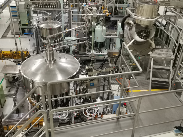 Eine große Reaktormaschine in einem Gebäude, umgeben von verschiedenen Komponenten und Maschinen, mit einem Boden, Geländern und Treppen.