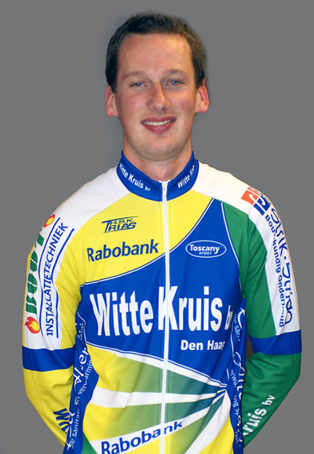 Ein Sportler posiert für ein Foto und trägt ein T-Shirt mit den Namen verschiedener Sponsoren.