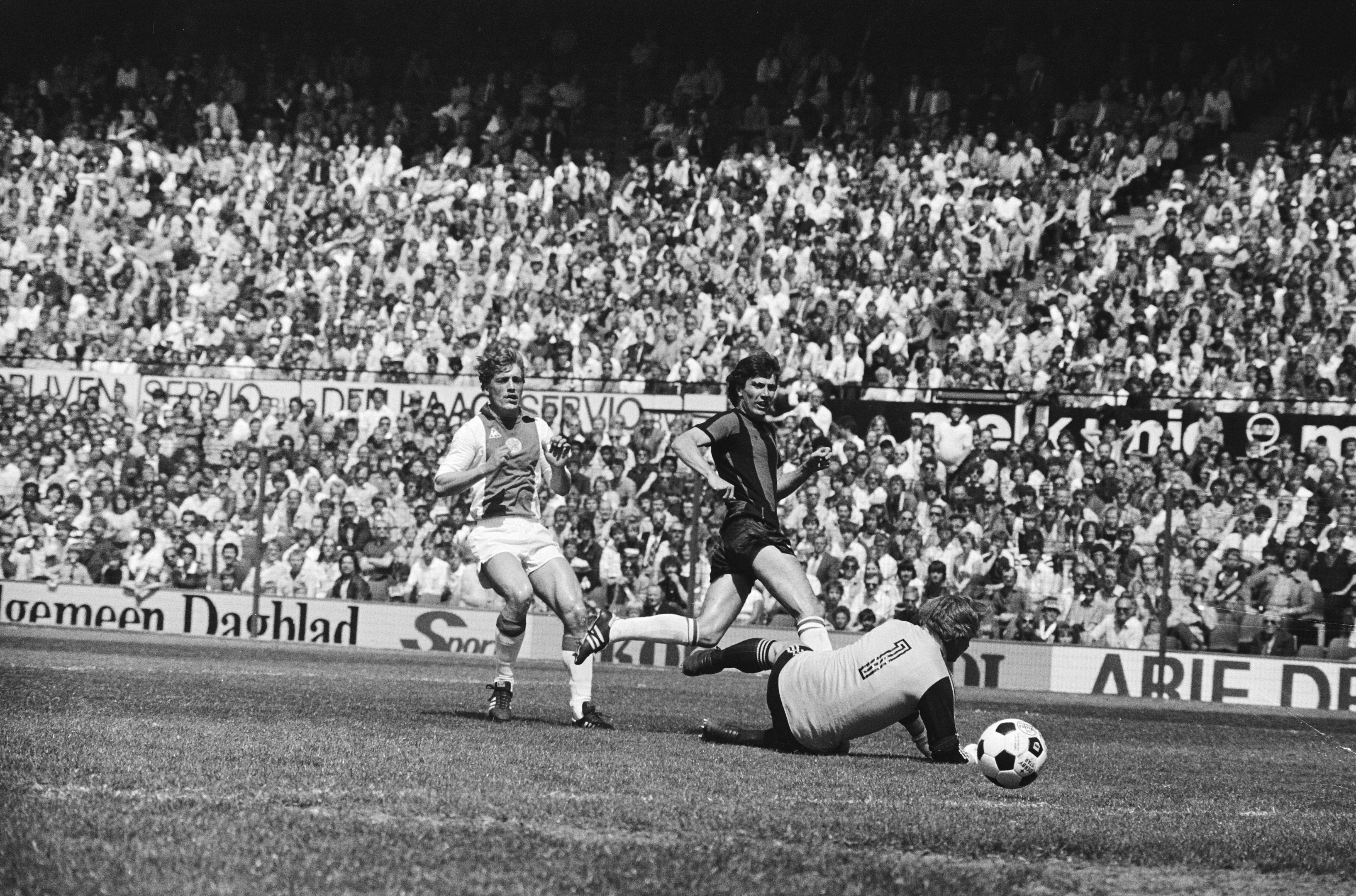 Schwarzes und weißes Foto von Fußballspielern im Einsatz auf einem Feld mit Zuschauern im Hintergrund und einem Banner mit der Aufschrift "Bundesliga 1978-79 Ajax 1-1 Hannover 96".