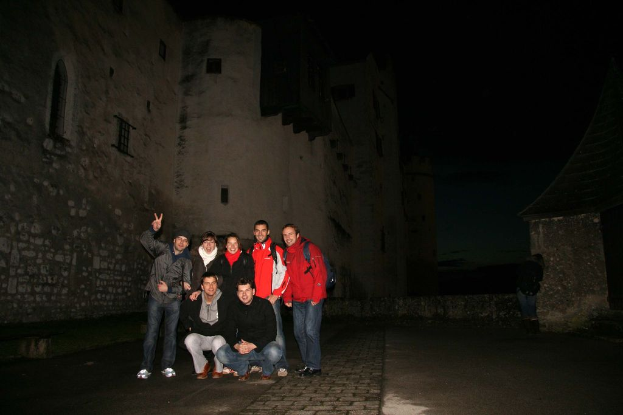 Eine Gruppe von Menschen steht vor einem Schloss in der Nacht.