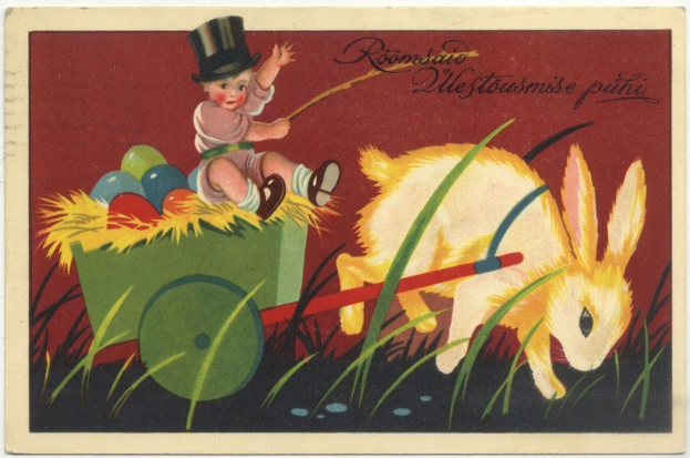 Alte Postkarte mit einem Baby in einem Zylinder, das einen mit bunten Ostereiern gefüllten Karren schiebt, begleitet von einem Hasen, mit handgeschriebenen Ostergrußen.
