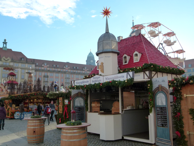 Ein geschäftiger Weihnachtsmarkt in Nürnberg, Deutschland mit Menschen um dekorierte Stände, festliche Lichter, ein Riesenrad, Gebäude und ein Schild rechts.