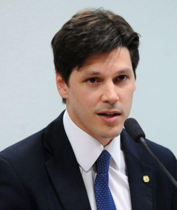 Ein Mann im Anzug und Krawatte spricht in ein Mikrofon, wahrscheinlich um die Genehmigung eines Gesetzes durch die Regierung zu kommentieren.