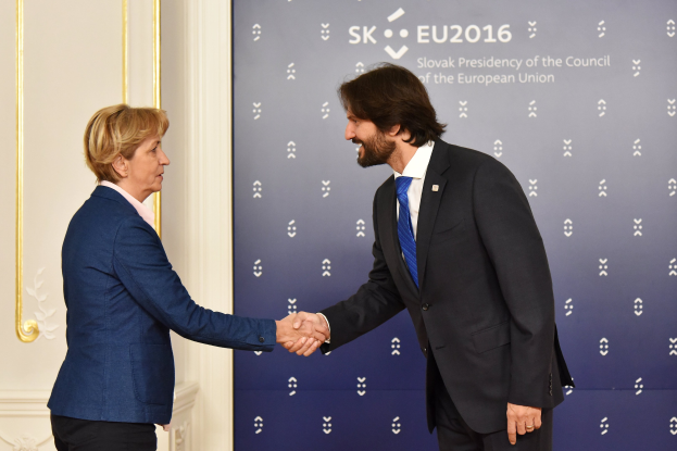 Bundeskanzlerin Angela Merkel und Bundespr├Ąsident Joachim Gauck schütteln sich vor einem "EU-Gipfel"-Plakat die H├Ąnde und l├Ącheln freundlich.