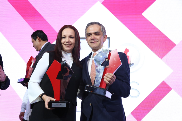 Zwei strahlende Menschen mit Trophäen auf einer Bühne.