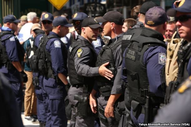 Eine Gruppe von Polizisten in Uniform, die zusammen auf einer Straße stehen, einige halten Waffen, mit Gebäuden und Schildern im Hintergrund.