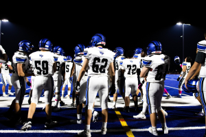 Eine Gruppe von Fußballspielern in Helmen und Stiefeln steht auf einem Feld, mit Hintergrundbeleuchtung.