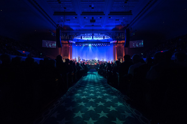 Großer Auditorium mit Sitzplätzen, Bühne mit Musikern und Deckenbeleuchtung und -bildschirme, typisch für eine 2019 Nationale Convention Konzerthalle.