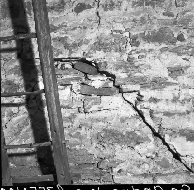 Schwarz-weißes Foto einer Leiter, die an einer Wand mit einem Riss lehnt, mit Text unten.