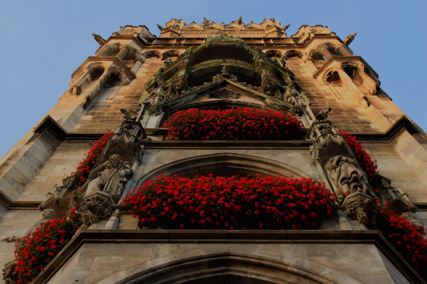 Eine Burg mit Statuen und Blumen im Vordergrund, mit einem Himmel im Hintergrund.