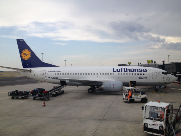 Lufthansa Airbus A320-200 Flugzeuge am Frankfurt Airport geparkt mit Bodenbetriebsfahrzeugen, Verkehrskegeln und Informationsschildern im Hintergrund unter einem bewölkten Himmel.