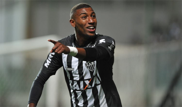 Fußballspieler in schwarzer und weißer gestreifter T-Shirt, der grinsend und einen Treffer feiernd mit einem unscharfen Hintergrund zu sehen ist.