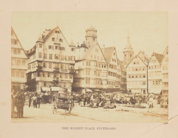 Altes Schwarz-Weiß-Foto eines belebten Marktplatzes in Stuttgart, Deutschland, mit mehrstöckigen Gebäuden, Passanten, horse-drawn carts und verschiedenen Marktständen; handschriftlicher Text erscheint entlang der unteren Kante.