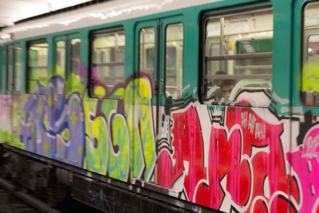 Ein Zug auf Schienen mit zwei Personen darin und Graffiti an seiner Außenseite.