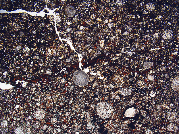 Nahaufnahme einer rissigen, schmutzigen Straße mit rauer Textur durch eingelassene Steine.