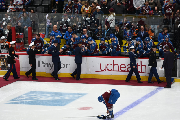 Hockeyspieler auf dem Eis umgeben von Teamkollegen und Gegnern, mit Zuschauern im Hintergrund bei einem NHL-Spiel von Colorado Avalanche gegen San Jose Sharks am 24. März 2015.