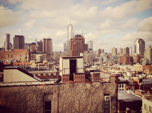 Eine Luftaufnahme einer Stadt mit zahlreichen ├╝ber das Landschaftsbild verstreuten Geb├Ąuden unter einem bew├Âlktem Himmel.