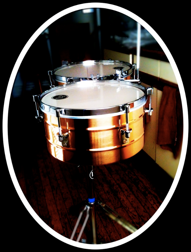 Eine Sammlung von Musikinstrumenten, einschließlich einer Gitarre, einem Saxophon und einem Schlagzeug, die auf einem Holzboden angeordnet sind.