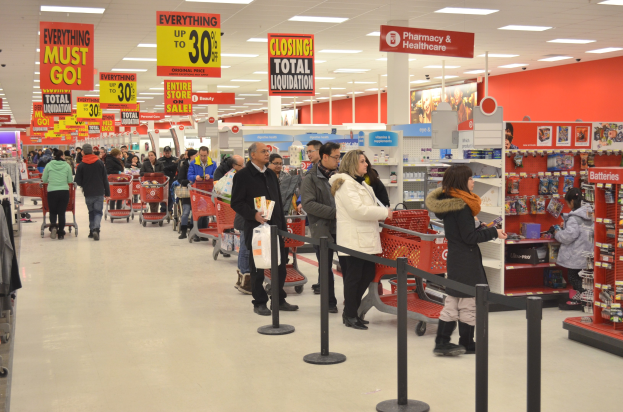 Ein volles Walmart-Geschäft mit Einkaufstüten tragenden Kunden und Einkaufswagen, mit Regalen, Schildern und Deckenleuchten im Hintergrund.