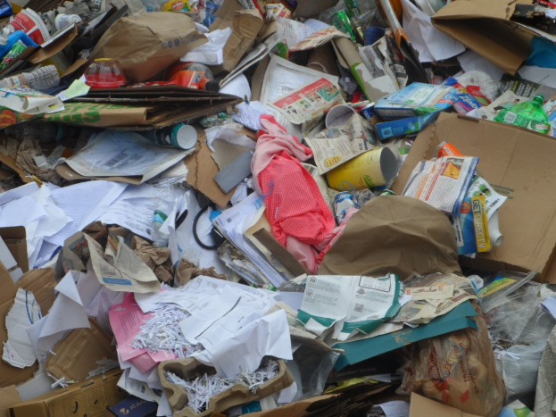 Ein unordentlicher Haufen aus Kartonschachteln mit Papieren, Flaschen, Abdeckungen und diversen Gegenständen.