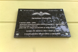 Eine schwarze Plakette mit wei├čer Schrift, die "Jaroslav Chmelik" lautet und von einem dekorativen Rahmen umgeben ist, die an einer Wand eines Geb├Ąudes angebracht ist.