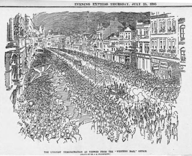 Schwarze und weiße Zeichnung einer Menge, die eine Straße zwischen Gebäuden entlanggeht, mit Text oben und unten: "Die Unionistendemonstration, wie sie vom Western Mail Office aus gesehen wird."