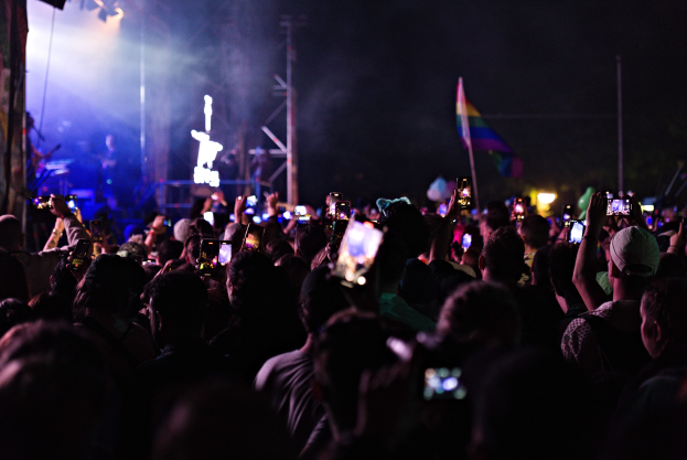 Eine Menge bei einem Konzert hält beleuchtete Handys hoch, während Musiker auf der Bühne spielen.