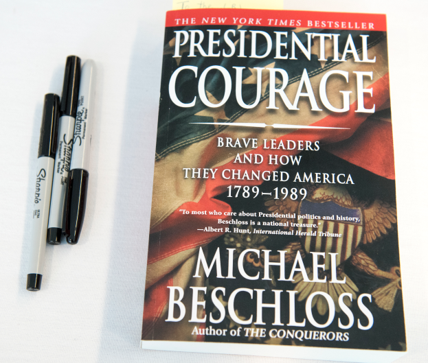Eine weiße Oberfläche mit einem Buch namens 'Präsidiale Courage: Mutige Führer und wie sie Amerika veränderten 1789-1989' von Michael Beschloss, begleitet von zwei Stiften.
